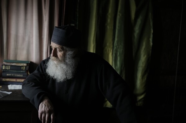 Orthodox Christian monk Father Spyridon of Amorgos, looks out from the chapel of the Monastery of Panagia Hozoviotissa, in Amorgos island, Greece, Sunday, March 30, 2025. (AP Photo/Petros Giannakouris)