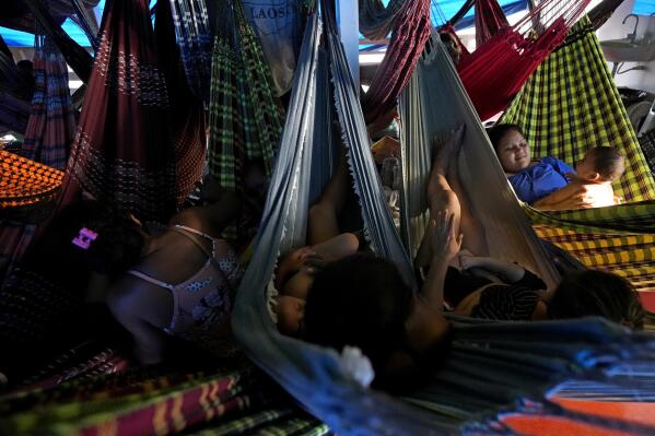 Passengers lounge in hammocks on a boat that travels from Macapa to the community of Vila Progresso, in the Bailique Archipelago, northern Brazil, Friday, Sept. 9, 2022. Sea erosion is swallowing houses, schools and other facilities in the area. (AP Photo/Eraldo Peres)