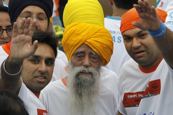 Centenarian marathon runner Fauja Singh, center, smiles after finishing a 10-kilometer race, held as part of the annual Hong Kong Marathon, in Hong Kong, Feb. 24, 2013. (AP Photo/Vincent Yu, file)