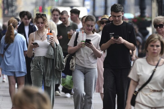 Pedestrians look at their phones while walking through St. Petersburg, Russia, on Monday, July 14, 2025. (AP Photo/Dmitri Lovetsky)