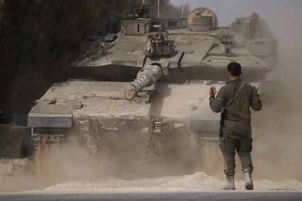 An Israeli soldier directs a tank at a staging area near the border with the Gaza Strip, in southern Israel, Tuesday, July 1, 2025. (AP Photo/Ariel Schalit)