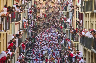 Revelers run alongside José Escolar Gil's fighting bulls during the sixth running of the bulls at the San Fermín Festival in Pamplona, Spain, Saturday, July 12, 2025. (AP Photo/Miguel Oses)
