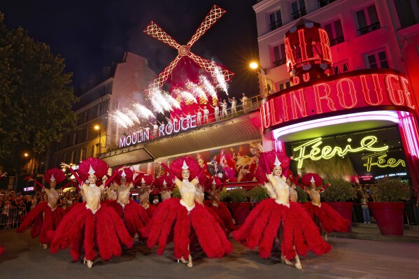 Dancers perform outside the Moulin Rouge cabaret to mark the mill's huge sails return to operation, Thursday July 10, 2025. (Moulin Rouge via AP)