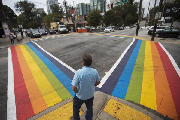 A pedestrian waits to cross a rainbow painted crosswalk in midtown to commemorate this weekend's annual Atlanta Pride parade Friday, Oct. 9, 2015, in Atlanta. (AP Photo/David Goldman, File)