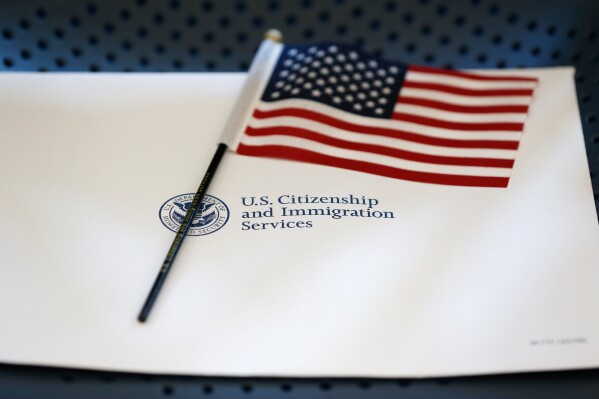 An information packet and an American flag are placed on a chair at the U.S. Citizenship and Immigration Services Miami Field Office on Aug. 17, 2018, in Miami. (AP Photo/Wilfredo Lee, File)