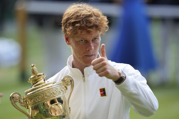 Italy's Jannik Sinner celebrates with the trophy after beating Carlos Alcaraz of Spain to win the men's singles final at the Wimbledon Tennis Championships in London, Sunday, July 13, 2025. (AP Photo/Kin Cheung)
