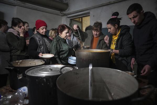 People queue to receive hot food in a improvised bomb shelter in Mariupol, Ukraine, Monday, March 7, 2022. (AP Photo/Evgeniy Maloletka)