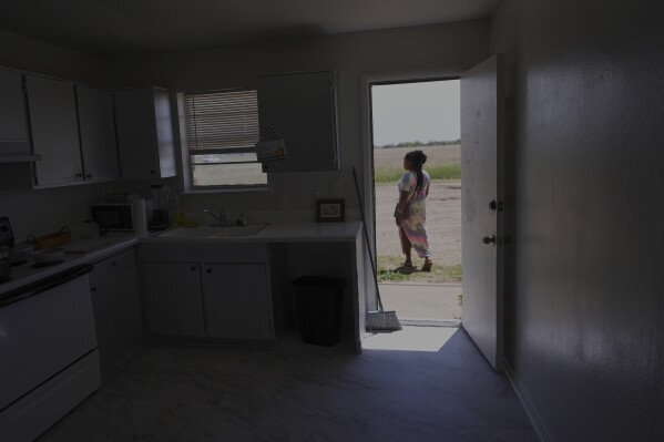 Nicole, a Haitian immigrant who works for a meat processing plant, looks for wild flowers outside her apartment, Sunday, April 13, 2025, in Dumas, Texas. (AP Photo/Eric Gay)