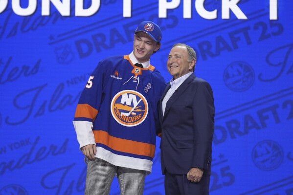 Matthew Schaefer, left, stands with NHL commissioner Gary Bettman after being drafted by the New York Islanders during the NHL hockey draft Friday, June 27, 2025, in Los Angeles. (AP Photo/Damian Dovarganes)