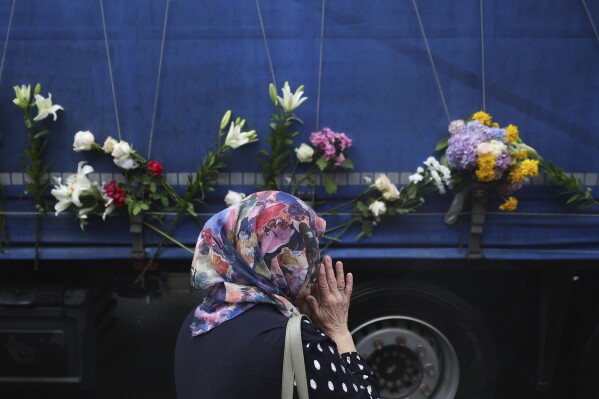 A women prays next to a truck carrying remains of the identified victims of the 1995 Srebrenica massacre to the Memorial centre in Potocari, where they will be buried on July 11, in Sarajevo, Bosnia, Wednesday, July 9, 2025. (AP Photo/Armin Durgut)