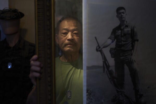 Hung Vu, 73, a former South Vietnamese army officer who left the country in 1975, poses with a photo of himself taken during the Vietnam War at his army surplus store in the Little Saigon neighborhood of Westminster, Calif., Tuesday, April 22, 2025. (AP Photo/Jae C. Hong)