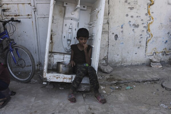 A Palestinian child waits for donated food at a community kitchen in Gaza City, in the northern Gaza Strip, Monday, July 14, 2025. (AP Photo/Jehad Alshrafi)