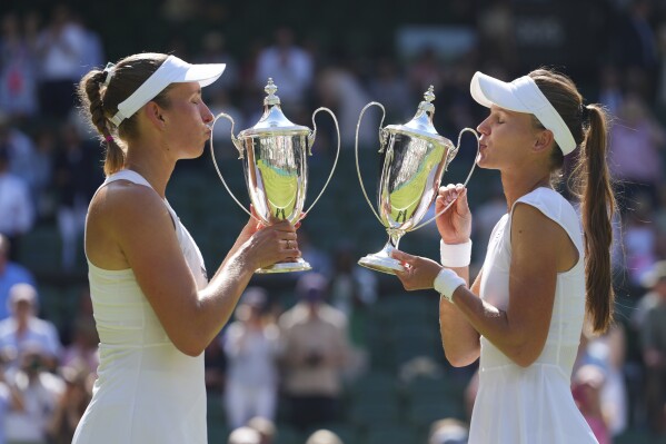Veronika Kudermetova of Russia,right, and Elise Mertens of Belgium celebrate with the trophies after winning against Jelena Ostapenko of Latvia and Su-Weih Hsieh of Taiwan their women's doubles final match at the Wimbledon Tennis Championships in London, Sunday, July 13, 2025.(AP Photo/Kirsty Wigglesworth)