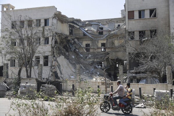 Gente pasa ante el edificio del Ministerio sirio de Defensa, que sufrió graves daños el miércoles por ataques aéreos israelíes en Damasco, Siria, el 17 de julio de 2025. (AP Foto/Ghaith Alsayed)