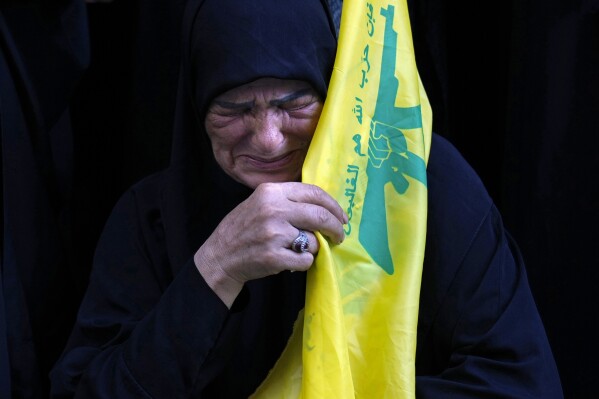 A woman carries the Hezbollah flag as she mourns during the funeral procession of Amira and Hassan Fadlallah, Wednesday, July 31, 2024, in Beirut, Lebanon. (AP Photo/Hussein Malla)