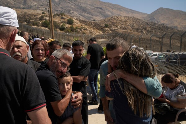 Druze from Syria hug relatives from Israeli Druze community before crossing the Israeli-Syrian border, in the town of Majdal Shams, in the Israeli-controlled Golan Heights, Thursday, July 17, 2025. (AP Photo/Leo Correa)