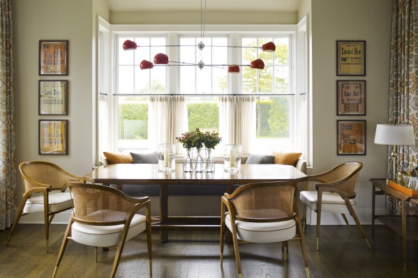 This image provided by Mendelson Group shows designer Gideon Mendelson's home in Sagaponack, New York. Mendelson framed some inexpensive yet eye-catching vintage deli signs for a playful element to the dining room. "Slow decorating" embraces a more deliberate approach that prioritizes a personal connection to the stuff we live with. (Eric Piasecki/OTTO via AP)