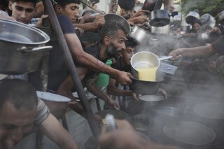 Palestinians struggle to get donated food at a community kitchen in Gaza City, northern Gaza Strip, Monday, July 14, 2025. (AP Photo/Jehad Alshrafi)