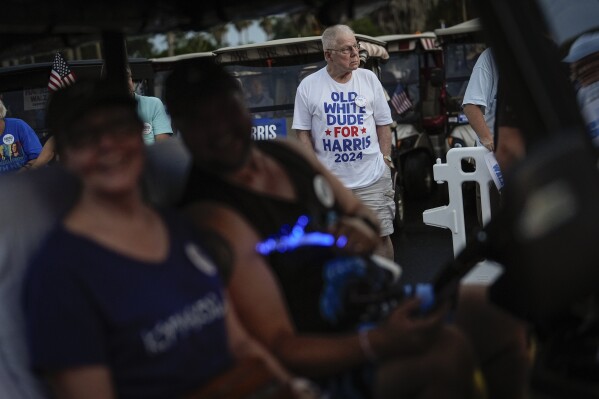 A man wears a tee-shirt reading "Old White Dudes for Harris" as he waits for second gentleman Doug Emhoff to kick-off a parade of decorated golf carts in support of Democratic presidential nominee Vice President Kamala Harris, at a campaign event in The Villages, Fla., Friday, Sept. 13, 2024. (AP Photo/Rebecca Blackwell)