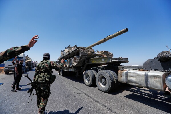 A tank for the Syrian government forces carried on a truck, which withdraw from Sweida city, pass on Daraa highway, southern Syria, Tuesday, July 15, 2025. (AP Photo/Omar Sanadiki)