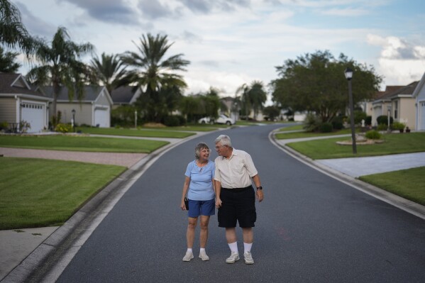 Retired attorney Howard Underwood, and his wife of 50 years, Janet, a retired IRS tax advisor, stand together for a portrait on their street in The Villages, Fla., Sunday, Sept. 15, 2024. The couple, who moved to The Villages in 2012, were Republicans for four decades before "Trump chased us out of the party." Now independents, "We've made common cause with the Democrats even though I don't share a whole lot of Kamala's ideas on things," said Howard. "The alternative is unthinkable." (AP Photo/Rebecca Blackwell)
