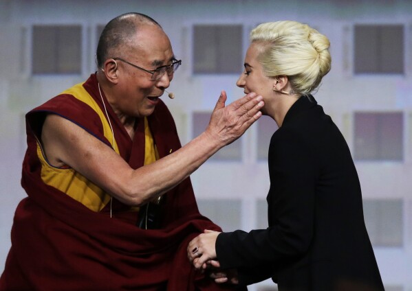 Tibetan spiritual leader the Dalai Lama greets Lady Gaga, right, before a question and answer session at the U.S. Conference of Mayors in Indianapolis, June 26, 2016. (AP Photo/Michael Conroy, File)