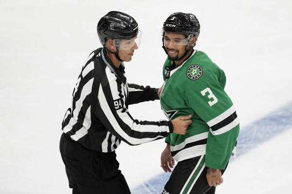 Linesman Bryan Pancich (94) holds Dallas Stars' Matt Dumba (3) back after a brief scuffle with Minnesota Wild players in the second period of a preseason NHL hockey game, Sept. 25, 2024, in Dallas. (AP Photo/Tony Gutierrez, File)