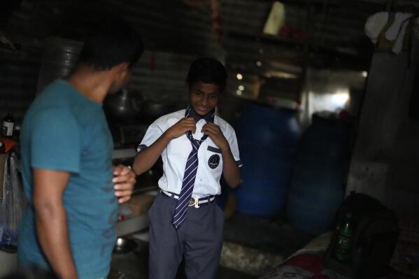 Raju, right, talks with his father Jaidul Islam after coming back from school at their home in a poor neighborhood in Bengaluru, India, Tuesday, July 19, 2022. A flood in 2019 in the Darrang district of India's Assam state started Raju, his sister Jerifa and their parents that led the family from their Himalayan village to the poor neighborhood. (AP Photo/Aijaz Rahi)
