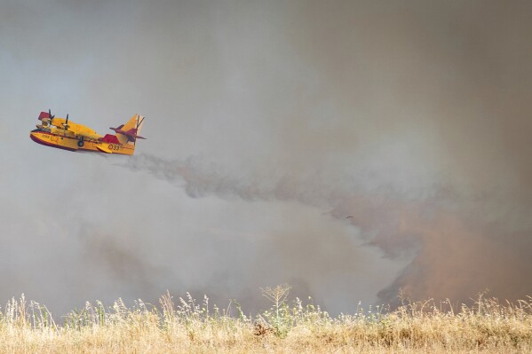 A firefighting plane drops water during efforts to extinguish a wildfire near Navalcarnero, on the outskirts of Madrid, Spain, Thursday, July 17, 2025. (A. Pérez Meca/Europa Press via AP)