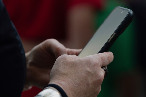A person looks at their phone at Seattle–Tacoma International Airport on Sunday, June 1, 2025, in Seattle. (AP Photo/Jenny Kane, File)