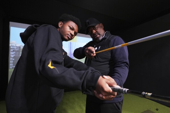 Shaun Horne, 16, a junior at Renaissance High School works on his swing with golf coach Jess Hawkins in Detroit, Thursday, Feb. 27, 2025. (AP Photo/Paul Sancya)