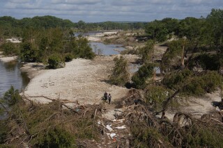 Search and rescue teams from Kerrville Fire Department walk past debris after flooding near the banks of the Guadalupe River in Kerrville, Texas on Tuesday, July 8, 2025. (AP Photo/Ashley Landis)