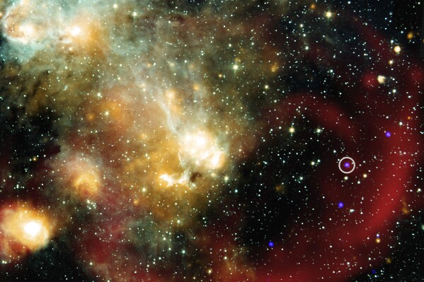 This image provided by NASA shows X-rays from NASA’s Chandra X-ray Observatory (represented in blue) that have been combined with infrared data from NASA’s retired Spitzer Space Telescope (cyan, light blue, teal and orange), and radio from MeerKat (red). An inset shows a more detailed view of the immediate area around this unusual object in X-ray and radio light. (NASA/Chandra/Spitzer/MeerKat via AP)