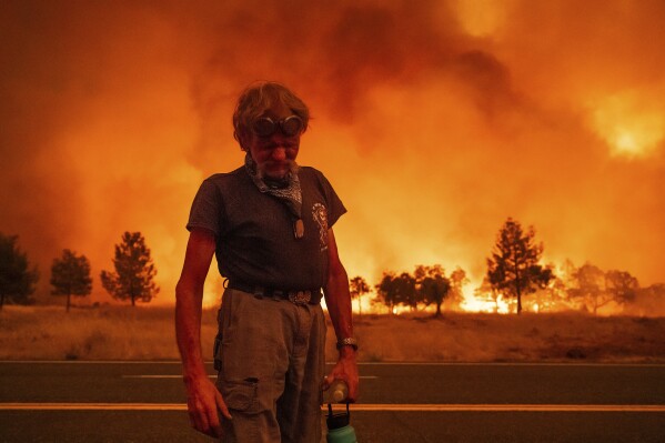 Grant Douglas pauses while evacuating as the Park Fire jumps Highway 36 near Paynes Creek in Tehama County, Calif., July 26, 2024. (AP Photo/Noah Berger)