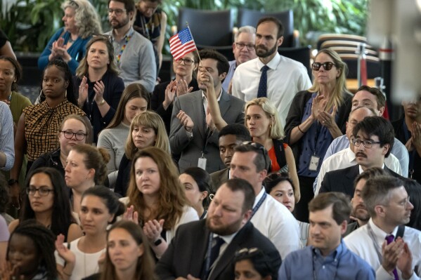 State Department employees applaud as their colleagues walk through the lobby of the State Department headquarters in the Harry S Truman Building, Friday, July 11, 2025, in Washington. (AP Photo/Mark Schiefelbein).