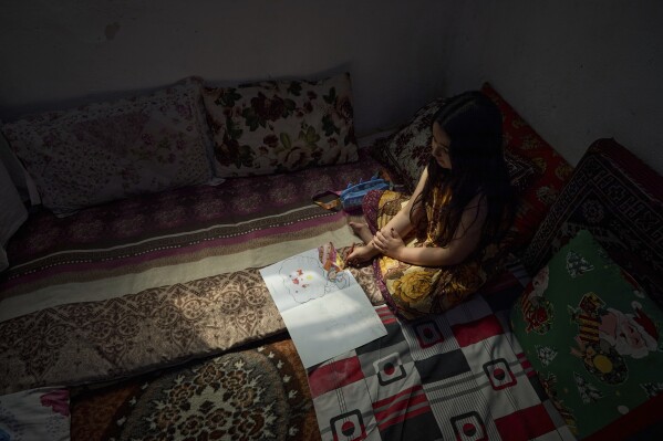 Nine-year-old Afghan girl Sara, whose family fled to Iran four years ago, draws in her room in Tehran, Iran, Wednesday, June 25, 2025, during the ceasefire after 12 days of Israeli bombardment. (AP Photo)