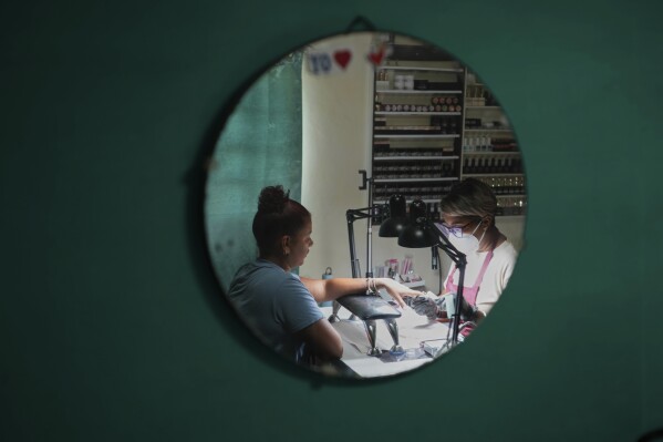 Manicurist Dayana Roche works on a client's nails at her home-run nail salon in Havana, Cuba, Thursday, June 26, 2025. (AP Photo/Ramon Espinosa)