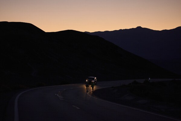 Danny Westergaard, left, competes with pacing help from daughter Madison Westergaard as the sun rises during the Badwater 135 Ultramarathon, Tuesday, July 8, 2025, in Death Valley National Park, Calif. (AP Photo/John Locher)