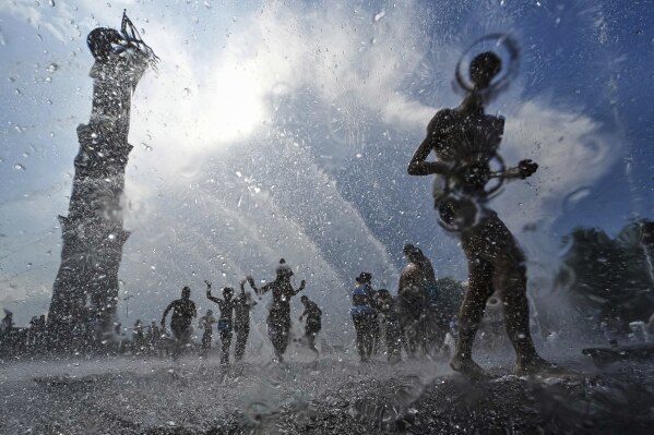 Children run through a water fountain in St. Petersburg, Russia, Saturday, July 12, 2025. (AP Photo/Dmitri Lovetsky)