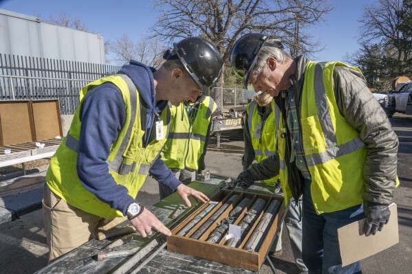 This undated photograph provided by the Denver Museum of Nature and Science shows James Hagadorn, left and Bob Raynolds examining a drilling core from the City Park core drilling in the parking lot at Denver Museum of Nature and Science. (Richard M Wicker/Denver Museum of Nature and Science via AP)