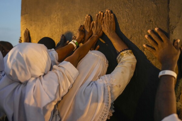 Muslim pilgrims prayers at top of the rocky hill known as the Mountain of Mercy, on the Plain of Arafat, during the annual Hajj pilgrimage, near the holy city of Mecca, Saudi Arabia, Saturday, June 15, 2024. (AP Photo/Rafiq Maqbool)