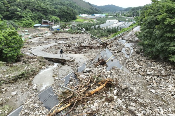 A road is covered with earth and rocks brought by a nearby landslide due to heavy rain at a village in Yesan, South Korea, Thursday, July 17, 2025. (Yoo Hyung-seok/Yonhap via AP)