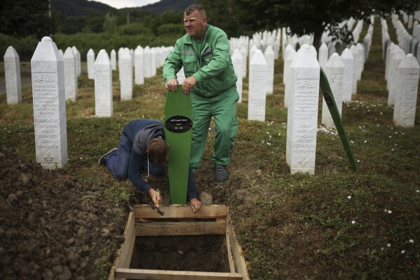 Cemetery workers prepare graves for a mass burial of seven newly identified victims of the 1995 Srebrenica Genocide in Potocari, Bosnia, Thursday, July 10, 2025. (AP Photo/Armin Durgut)