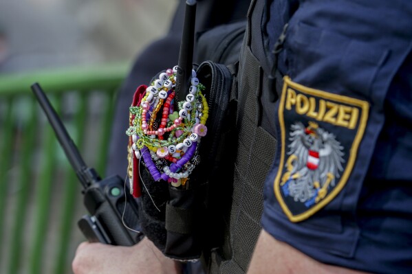 A police officer is decorated with Taylor Swift bracelets while guarding the city center in Vienna on Aug. 8, 2024. (AP Photo/Heinz-Peter Bader, File)