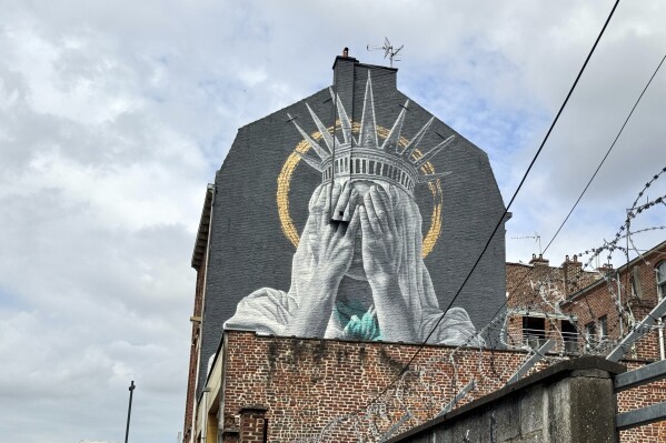 A mural by Dutch artist Judith de Leeuw shows the Statue of Liberty covering her eyes with her hands, in Roubaix, northern France, Monday, July 14, 2025. (AP Photo/Sylvain Plazy)